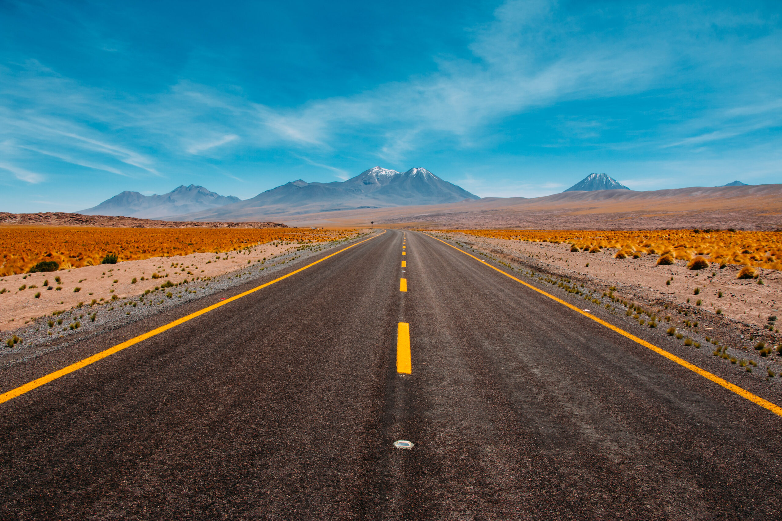 Highway leading to a blue horizon with mountains